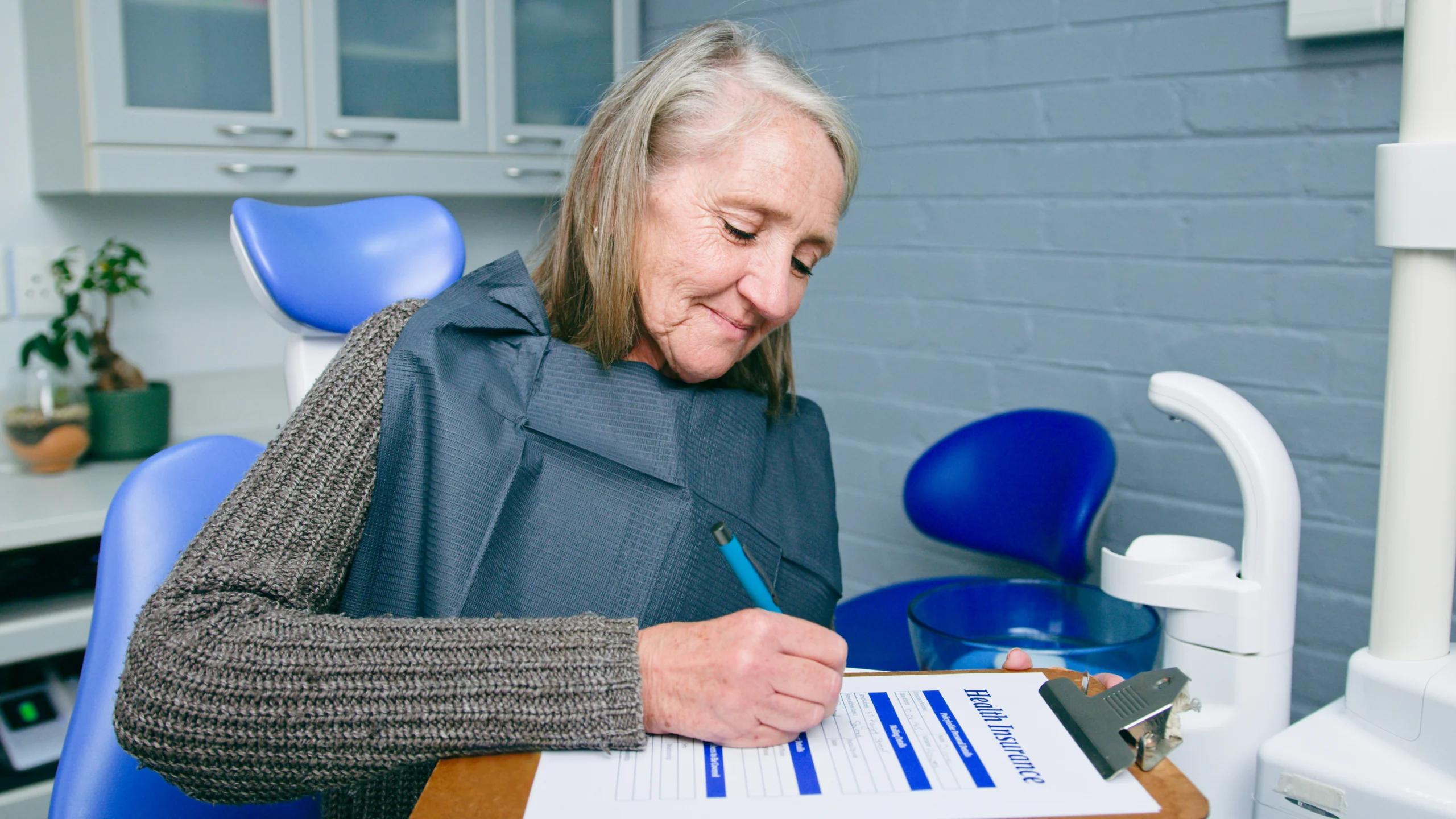 Senior Woman reading RJ Health Partners Dental Insurance Information while seated