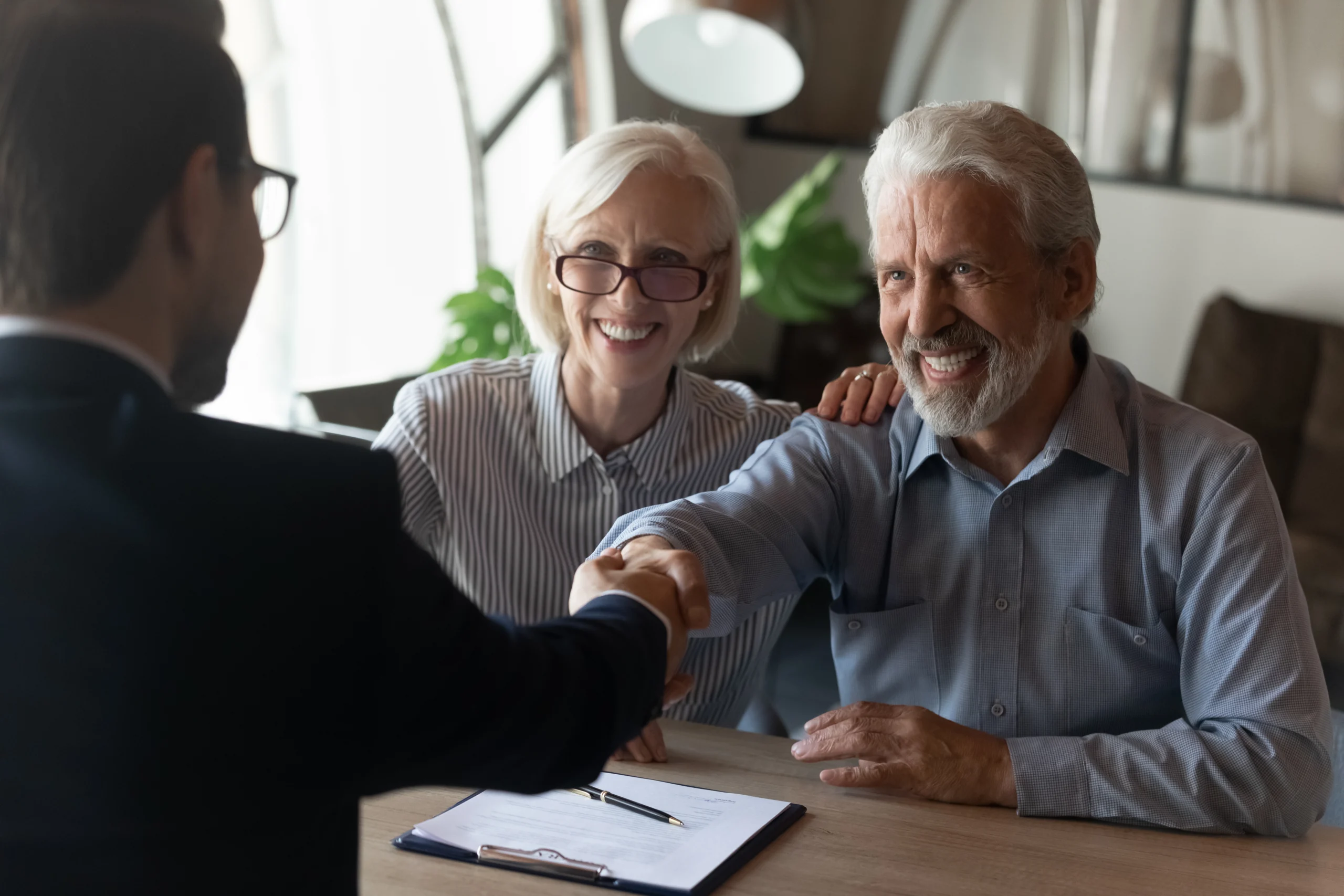 Seated older man shaking hands with agent