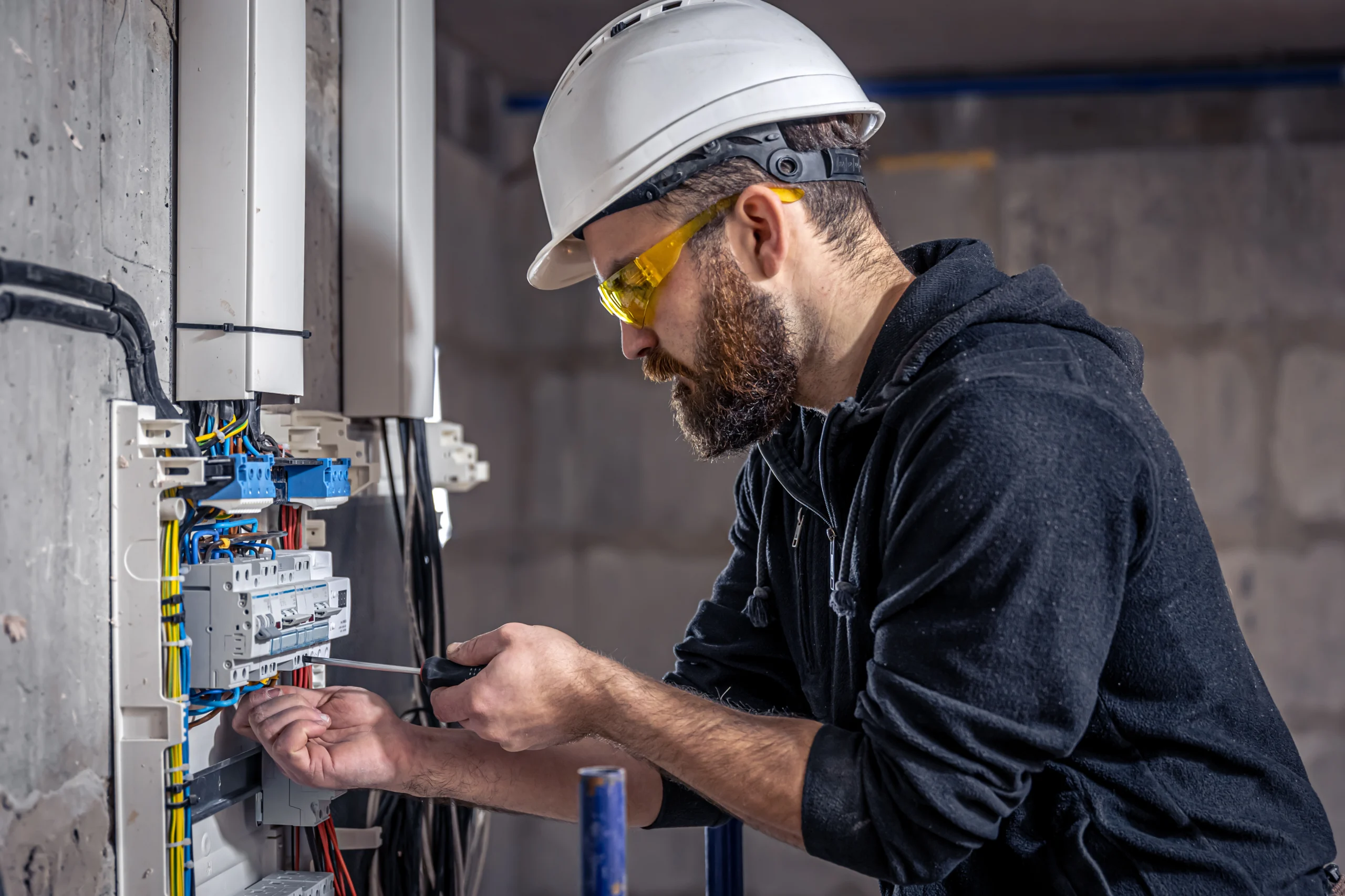 Self-Employed male electrician works in a switchboard with an electrical connecting cable Self-Employed male electrician works in a switchboard with an electrical connecting cable
