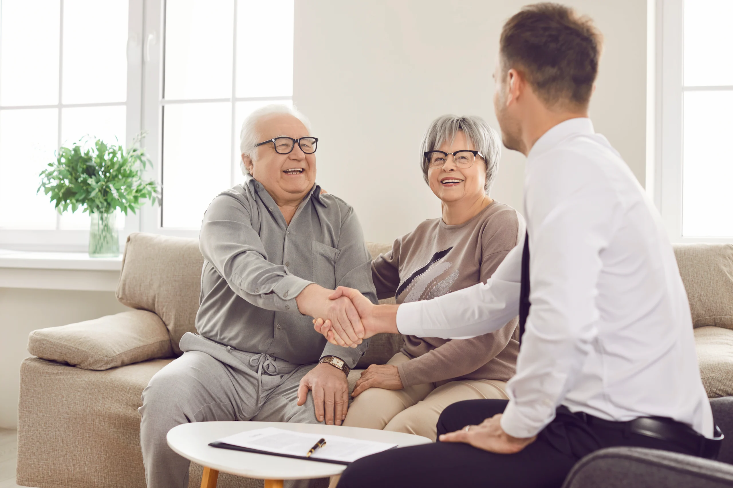 Seated smiling elderly person shaking hands with insurance agent